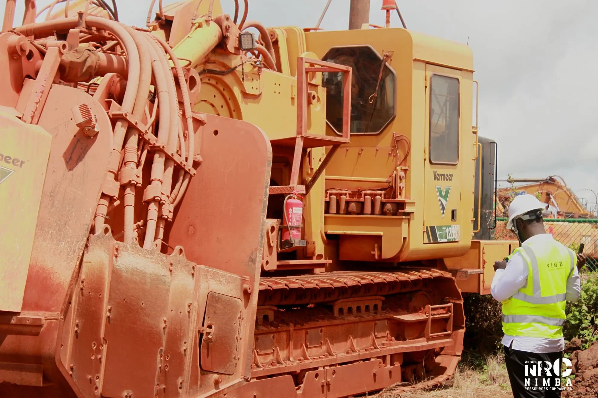 Personne en casque et gilet de sécurité NRC à côté d’un engin de terrassement sur chenilles