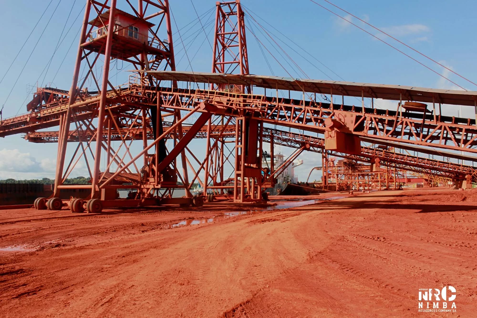 Convoyeurs et portiques de chargement d’un site portuaire sur un sol rouge de bauxite
